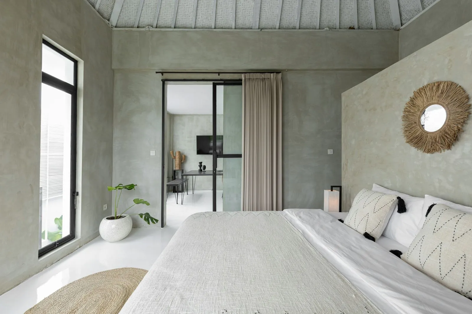 A bright bedroom featuring a white bed and a spacious window allowing natural light to fill the room.